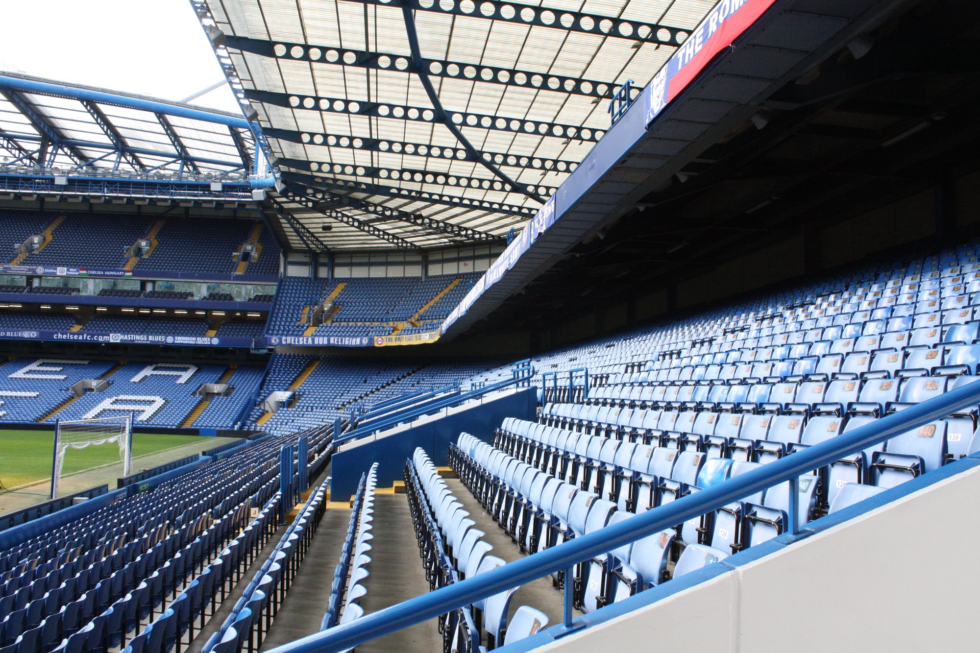Empty blue seats and roof structure inside Stamford Bridge